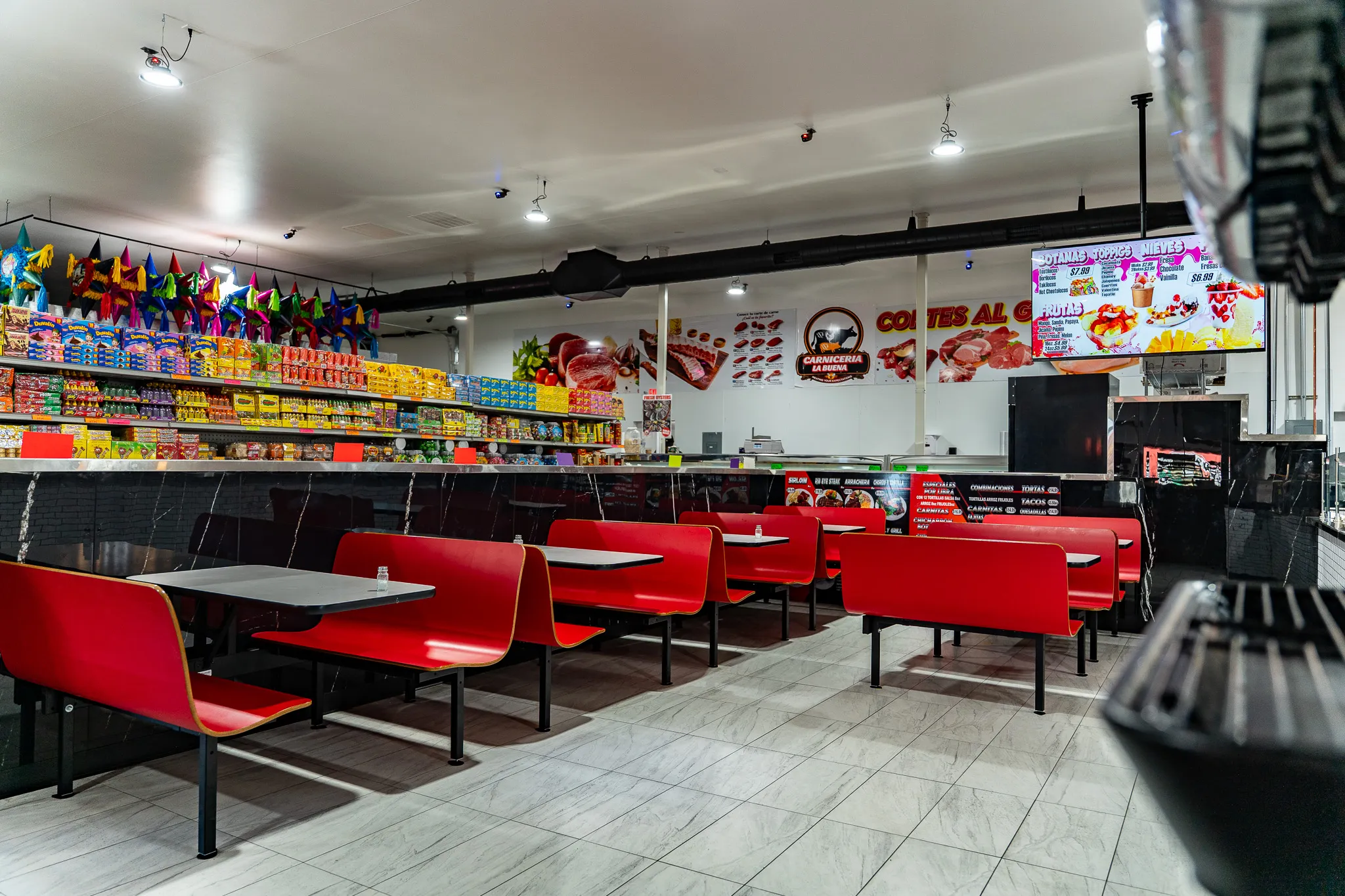 Colorful in-store dining area with red seating at Carnicería La Buena