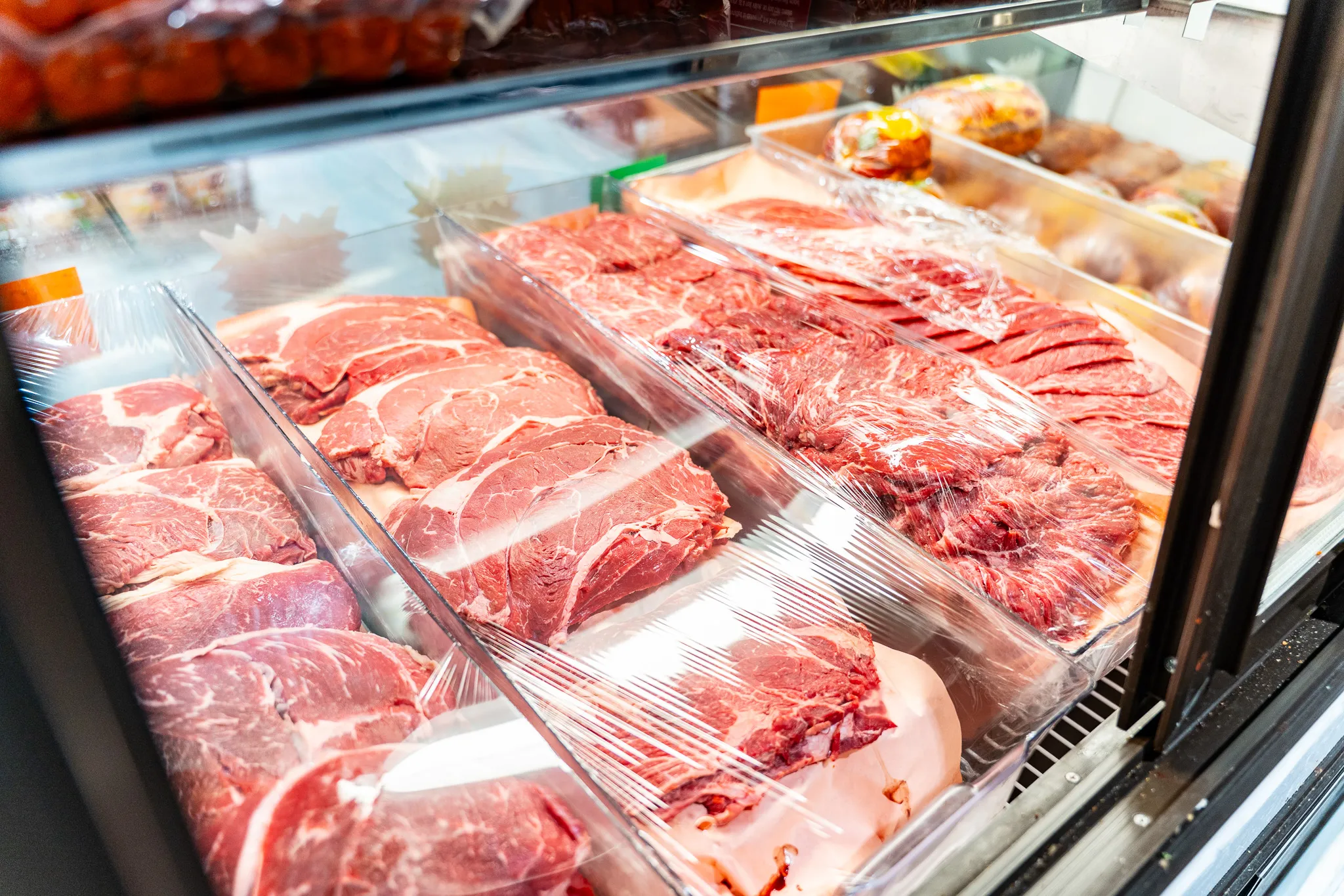 Display case of fresh, packaged cuts of meat at Carnicería La Buena