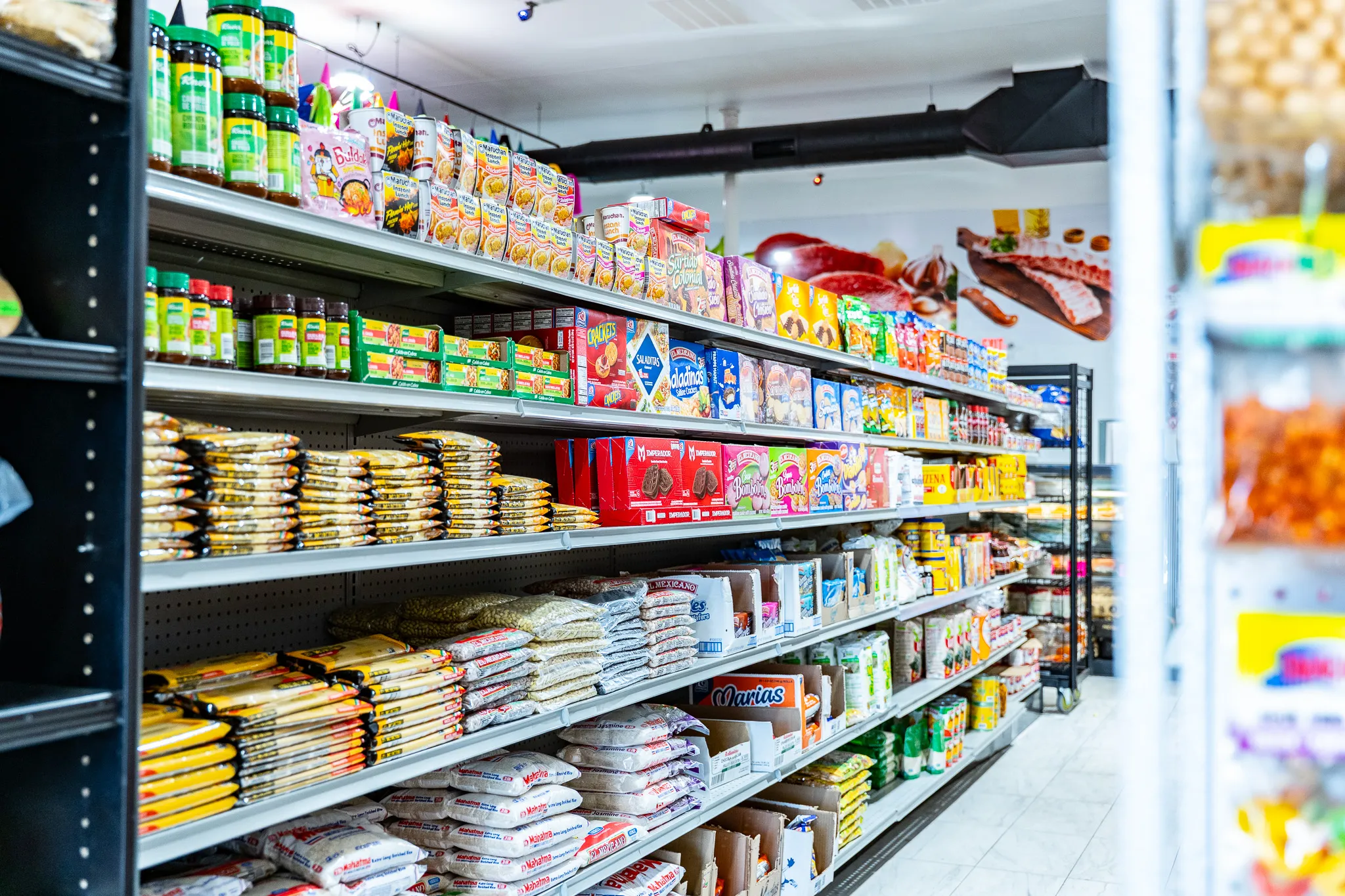 Brightly stocked grocery aisle of Mexican products and pantry staples inside Carnicería La Buena
