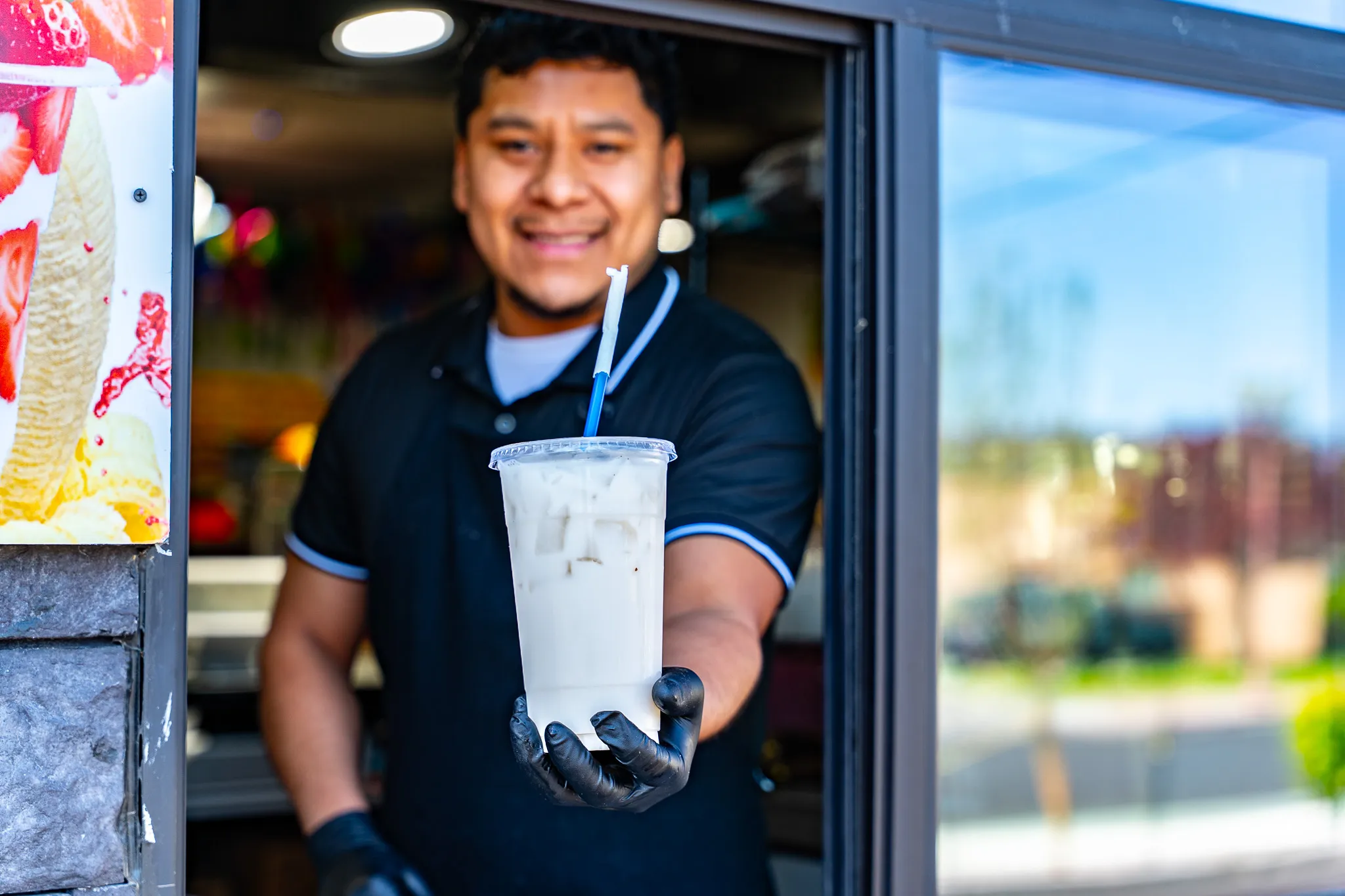 Friendly Carnicería La Buena team member smiling while serving a fresh agua fresca